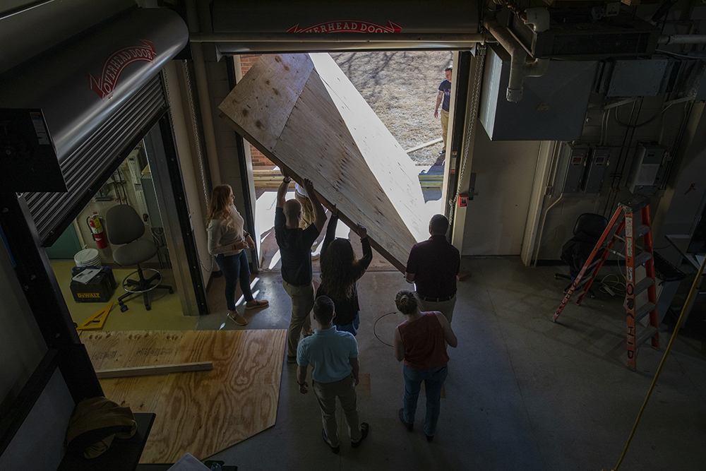 A group of participants carry a piece of wood out of the workshop to work on their decoy. (Credit: Sean McNeil)